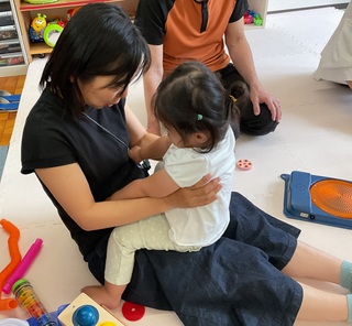 対象児が先生の膝にのって遊んでいます