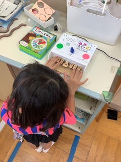小学生の女の子が点字タイプのおもちゃで遊ぶ様子。