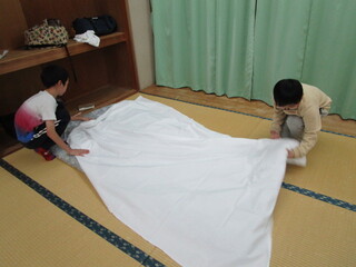友達と協力してシーツを敷く様子