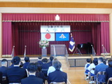 参加者が体育館のステージに向かって座っている様子
