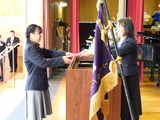 中学部卒業生女子が校長先生から卒業証書を授与されている場面