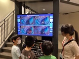 滑り台で滑った速さをモニターで確認する児童の様子