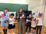 講師の先生と小学部児童がフィリピンの旗を持って集合 講師の先生と小学部児童がフィリピンの国旗を持って並んでいる写真