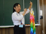 校長先生が千羽鶴を掲げて話をしている様子