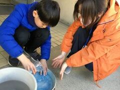 舎生がバケツに水を入れている様子。