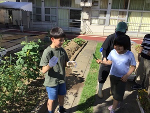 舎生２人が収穫したキュウリを持って喜んでいる様子。