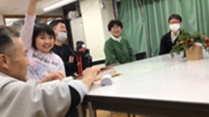 Aさんがクイズに答えようと手を挙げている様子。