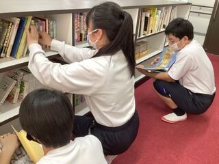 生徒たちが本棚から本を選んだり、本棚の前で読んだりしています