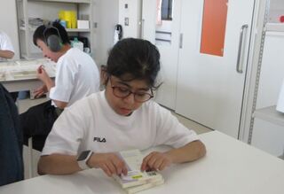 生徒が本の裏表紙にシールを貼ろうとしています